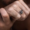 Mano masculina luciendo anillo Valurys de acero quirúrgico con diseño de dos serpientes entrelazadas.