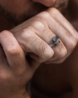 Mano masculina luciendo anillo Valurys de acero quirúrgico con diseño de dos serpientes entrelazadas.