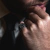 Hombre con barba apoyando el puño en su rostro, luce anillo Mosaico de acero quirúrgico Valurys con diseño geométrico decorativo.