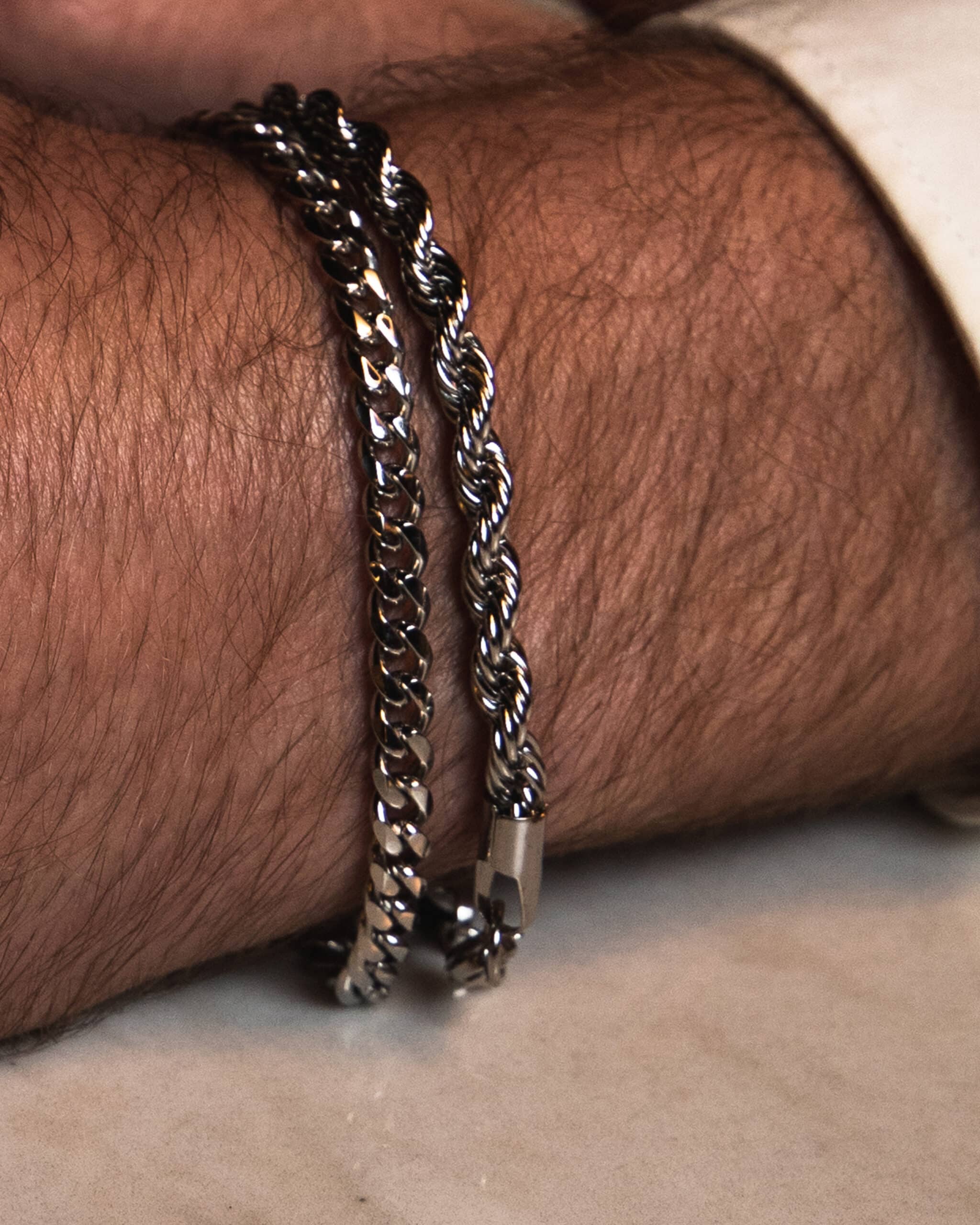 Pulseras de acero quirúrgico Valurys para hombre, modelos Cadena Fina y Cordón, combinadas para un look elegante.